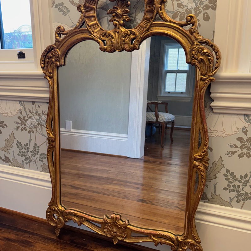 Hand-carved 19th-century giltwood mirror with ornate crest and warm patina.